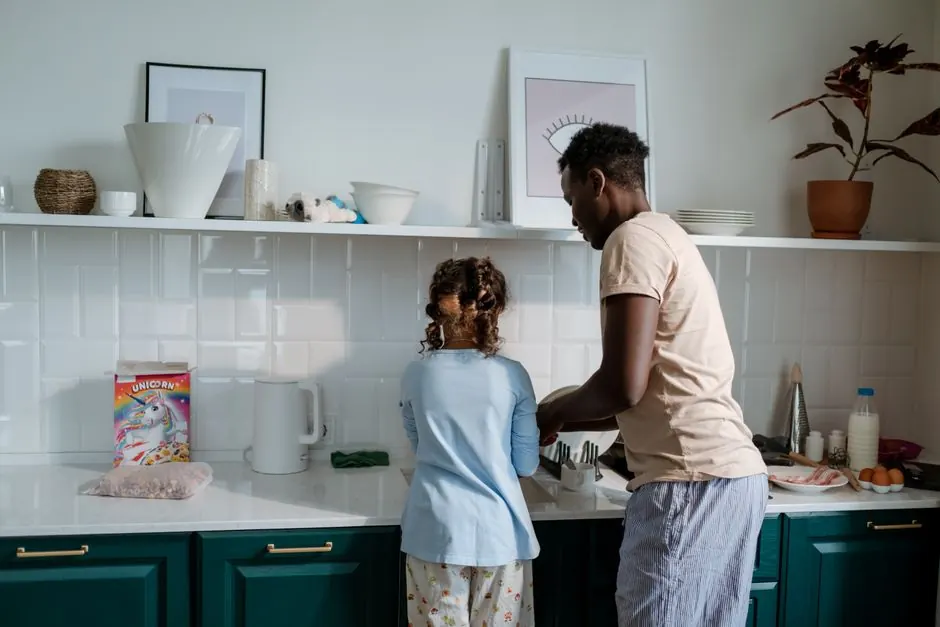 A father and daughter wash dishes together, fostering family bonds in a modern kitchen.