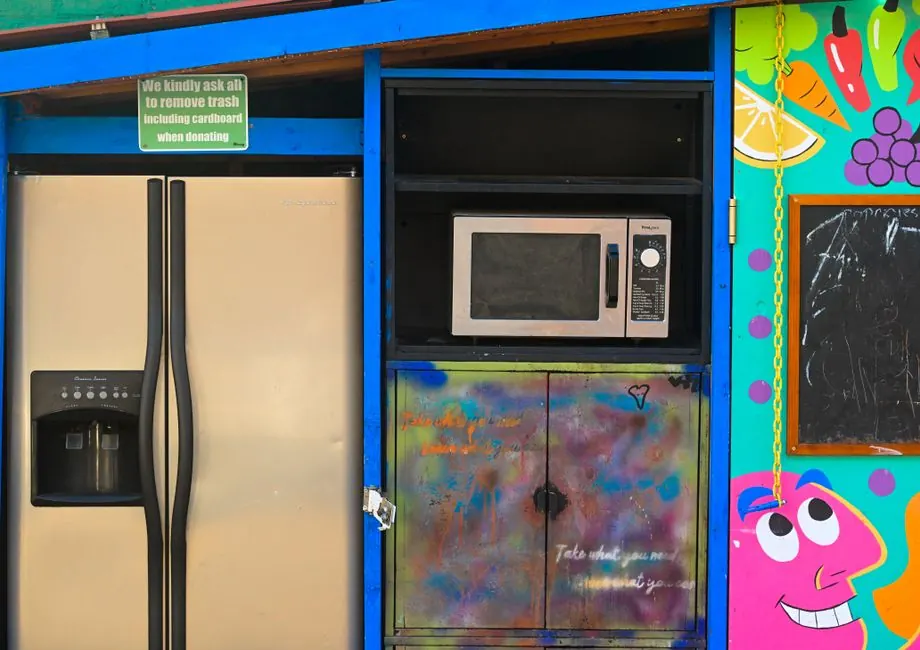 Brightly painted donation spot with a fridge, microwave, and colorful art.