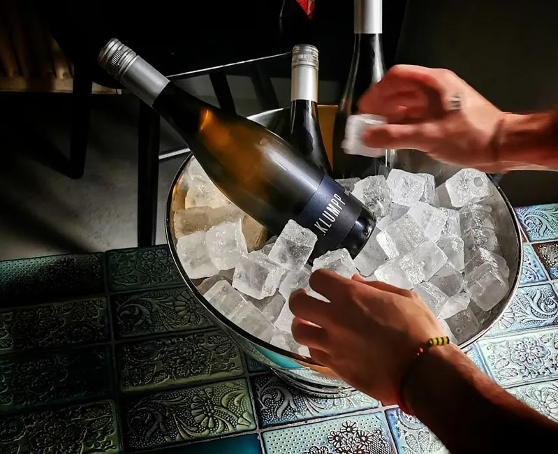 Close-up of wine bottles on ice in a bucket with vibrant tile background, creating a sophisticated atmosphere.