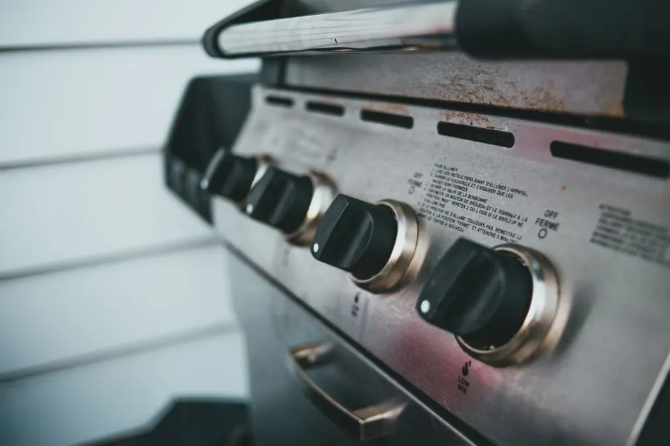 Detailed view of barbecue grill controls, showcasing knobs and stainless steel surface.